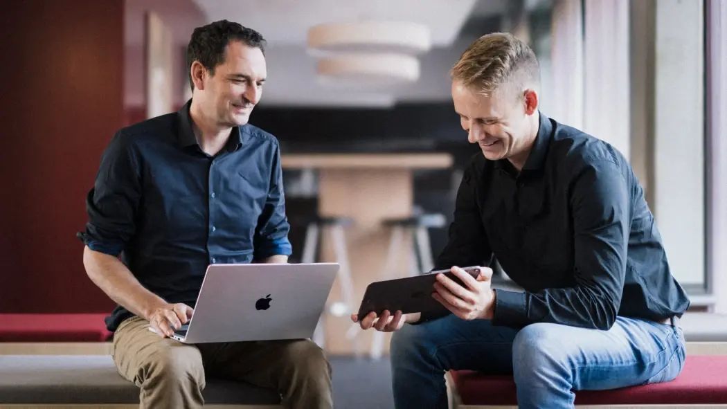 Zwei Mitarbeitende der Digital Marketing Agentur arbeiten an Laptop und Tablet